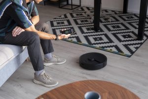 man controlling robot vacuum with his phone min